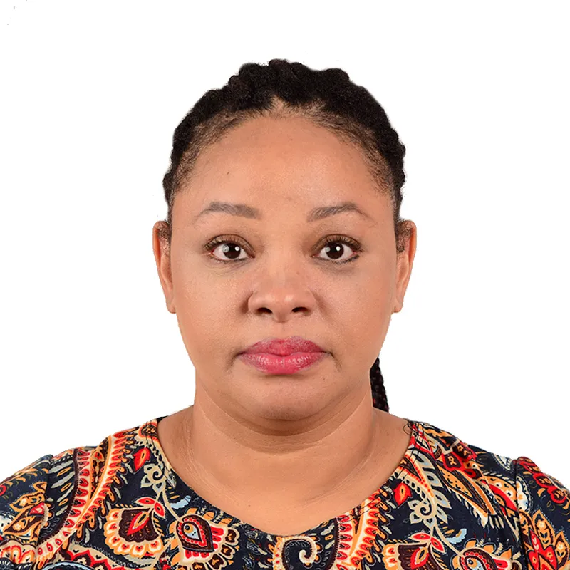 Portrait of a woman with braided hair wearing a colorful patterned top, looking directly at the camera with a neutral expression.