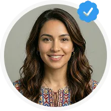 Smiling woman with long wavy dark hair wearing a colorful patterned top, with a blue verified checkmark badge overlay.