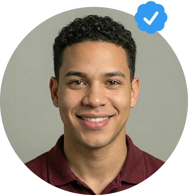 Portrait of a smiling young man with curly hair wearing a maroon shirt, with a blue verified checkmark badge at the upper right.